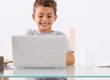 Kid smiling and working at a laptop