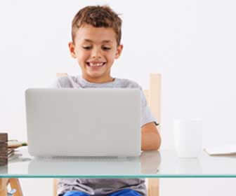 Kid smiling and working at a laptop