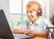 Young boy with headset at laptop for online class